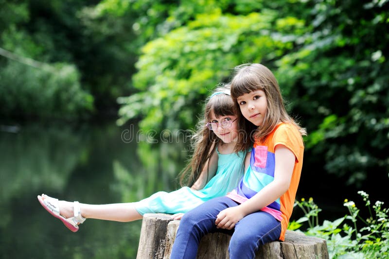 Little girls sitting on stump