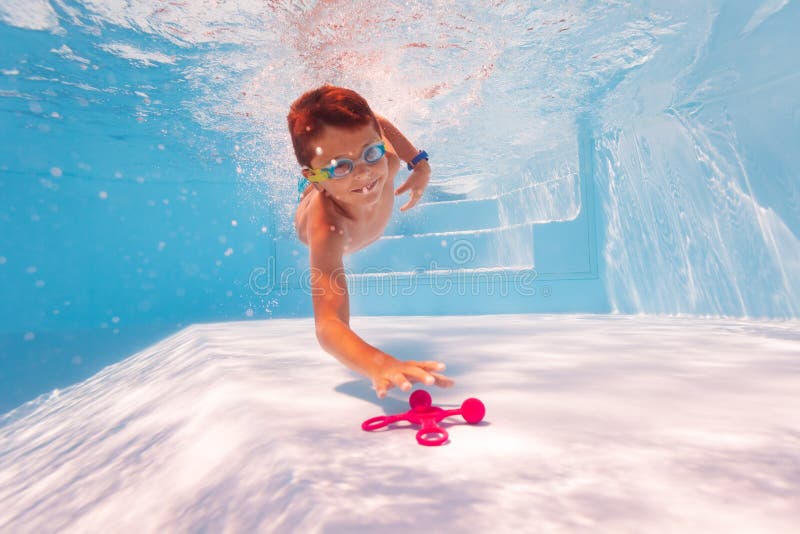 Cute boy dive and swim for toy on pool bottom