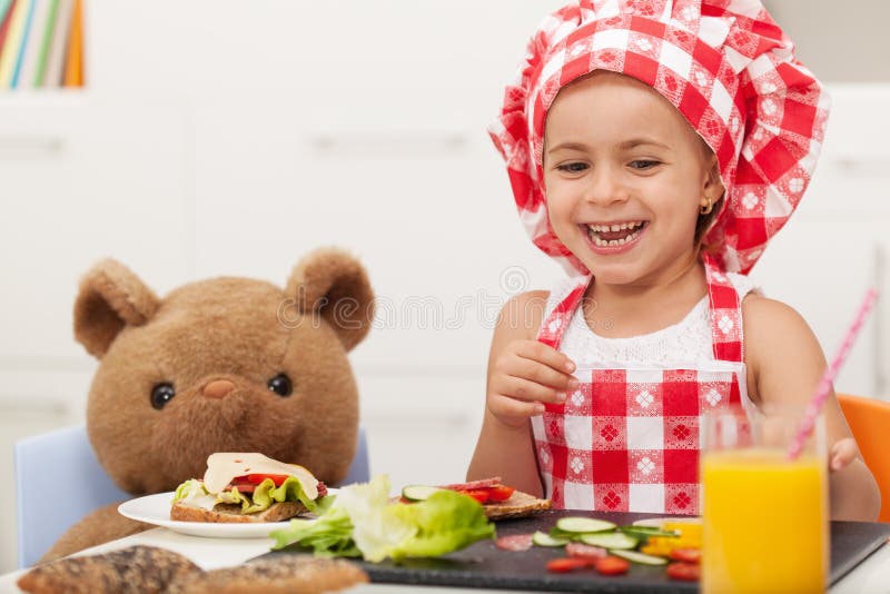 Little happy girl having a snack with her teddy bear stock images Little happy girl having a snack with her teddy bear stock images