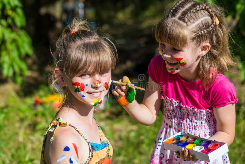 Little happy sisters play with colors in the park, children play, children paint each other