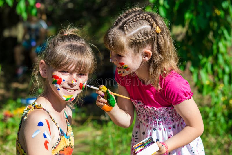 Little happy sisters play with colors in the park, children play, children paint each other