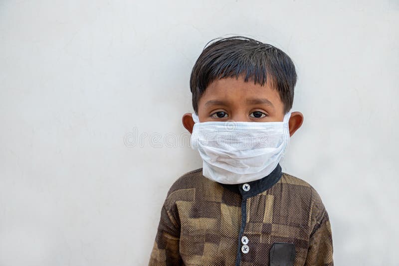 Little Indian Kid wearing surgical mask to get protected from spreading Coronavirus,originating in Wuhan, China. infected patient. Against white background stock photography Little Indian Kid wearing surgical mask to get protected from spreading Coronavirus,originating in Wuhan, China. infected patient. Against white background stock photography