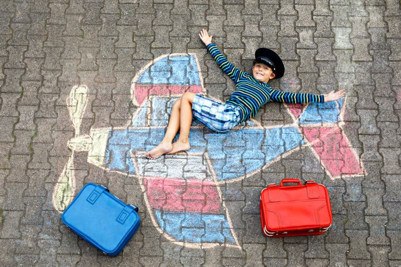 Little kid boy having fun with with airplane picture drawing with colorful chalks on asphalt. Child painting with chalk. And crayon and going on vacations or stock photo Little kid boy having fun with with airplane picture drawing with colorful chalks on asphalt. Child painting with chalk. And crayon and going on vacations or stock photo