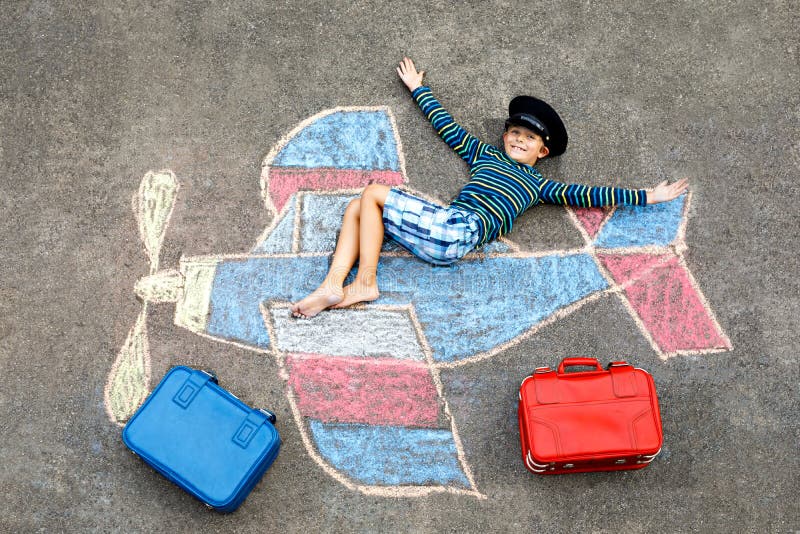 Little kid boy having fun with with airplane picture drawing with colorful chalks on asphalt. Child painting with chalk. And crayon and going on vacations or stock images Little kid boy having fun with with airplane picture drawing with colorful chalks on asphalt. Child painting with chalk. And crayon and going on vacations or stock images
