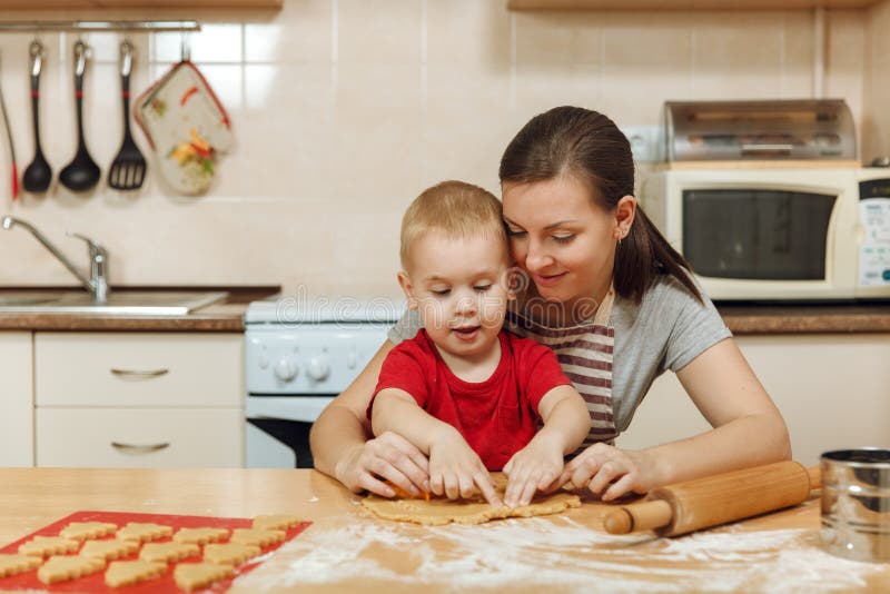Little kid boy helps mother to cook ginger biscuit. 