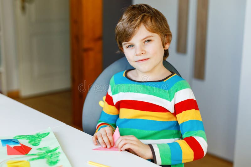 Little kid boy making paper origami tulip flowers for a postcard for mother& x27;s day or birthday. Cute child of elementary class school doing handicraft. Creative leisure for children. Little kid boy making paper origami tulip flowers for a postcard for mother& x27;s day or birthday. Cute child of elementary class school doing handicraft. Creative leisure for children.