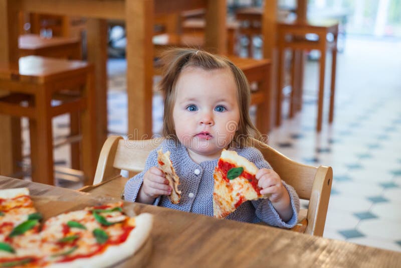 Little kid eating pizza appetizing, concept of baby eating.