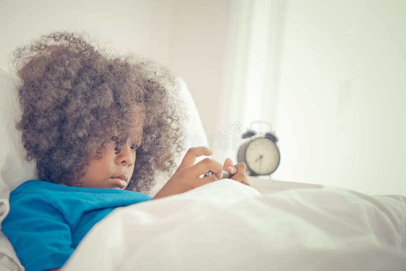Little kid using mobile phone to watch cartoon video in the morning bed stock photo Little kid using mobile phone to watch cartoon video in the morning bed stock photo