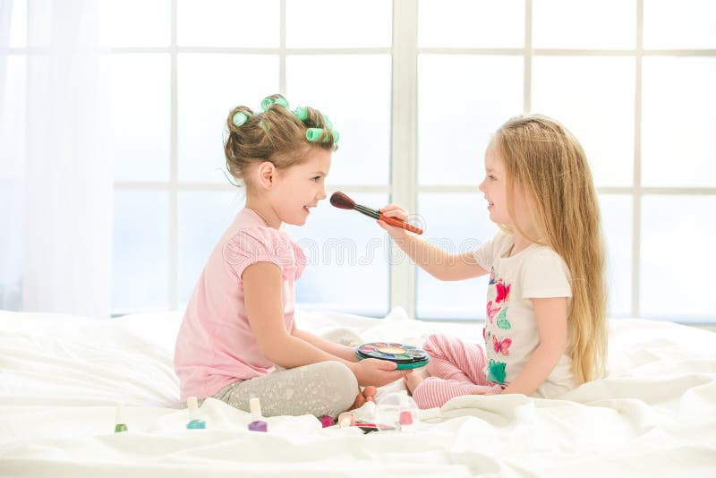 Little girl sisters. Маленькая девочка делает макияж. Девочка делает макияж сестре. Девочка с мамой красятся. Маленькая девочка делает макияж фото.