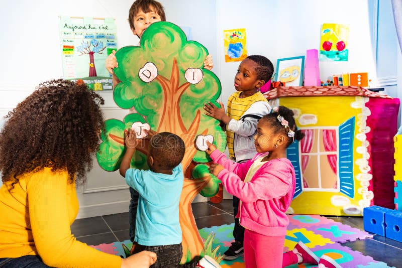 Little kids in nursery put letters on the tree stock images Little kids in nursery put letters on the tree stock images