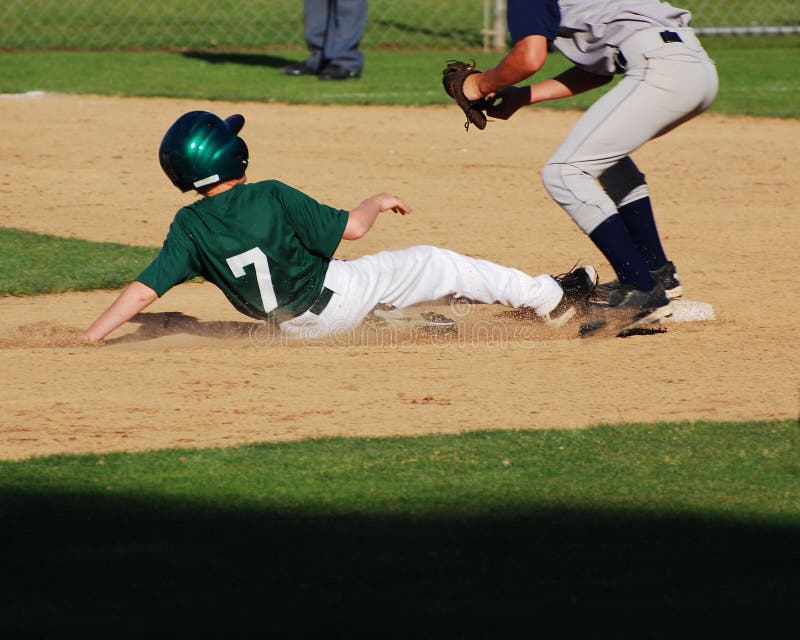 A baseball player sliding into 2nd base just before the 2nd baseman catches the ball. A baseball player sliding into 2nd base just before the 2nd baseman catches the ball.