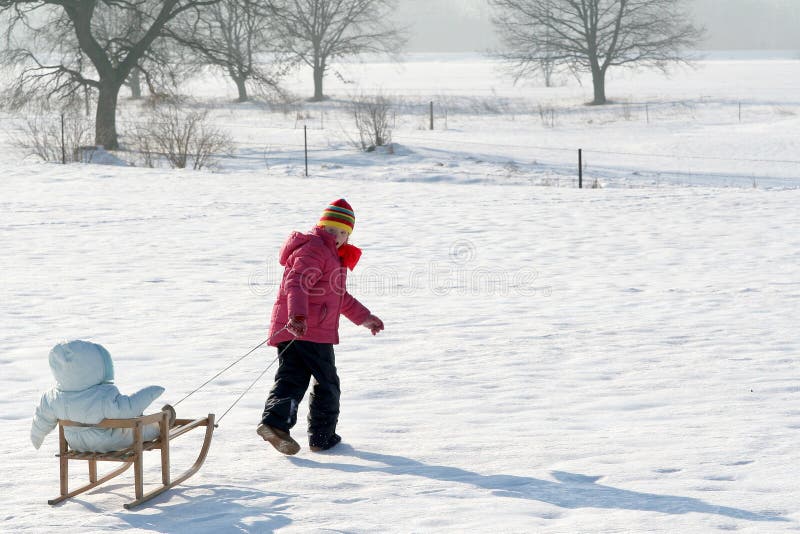 A little girl pulling a baby in sled. A little girl pulling a baby in sled