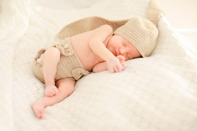 Little newborn baby sleeping and wearing crocheted clothes.