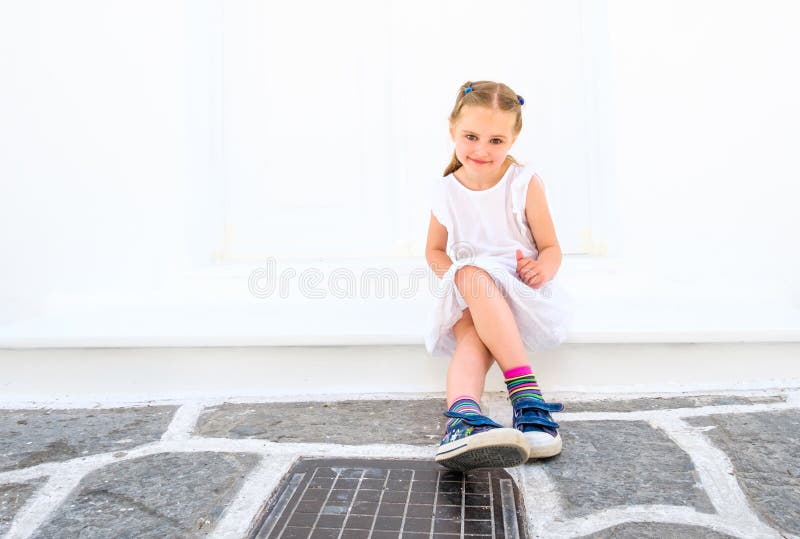 Little pretty blong girl in a white dress sitting outdoor stock image Little pretty blong girl in a white dress sitting outdoor stock image
