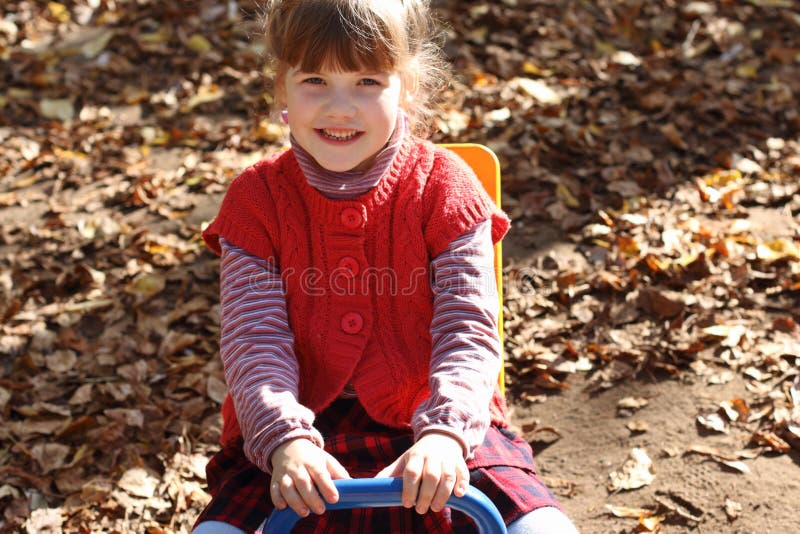 Little pretty smiling girl sits on wooden seesaw stock image Little pretty smiling girl sits on wooden seesaw stock image