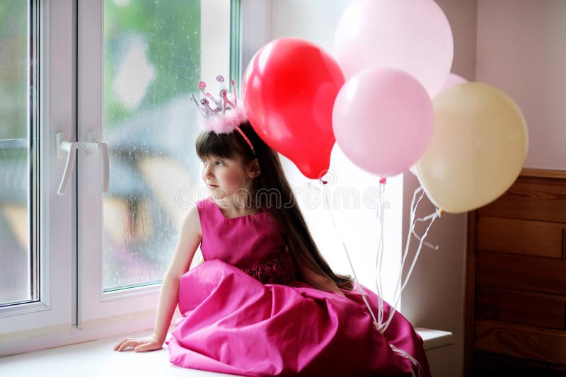 Little princess in pink dress holding baloons