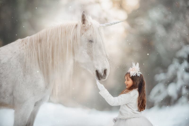 The little princess with an unicorn in the forest. The little girl with a white horse-unicorn in a winter park