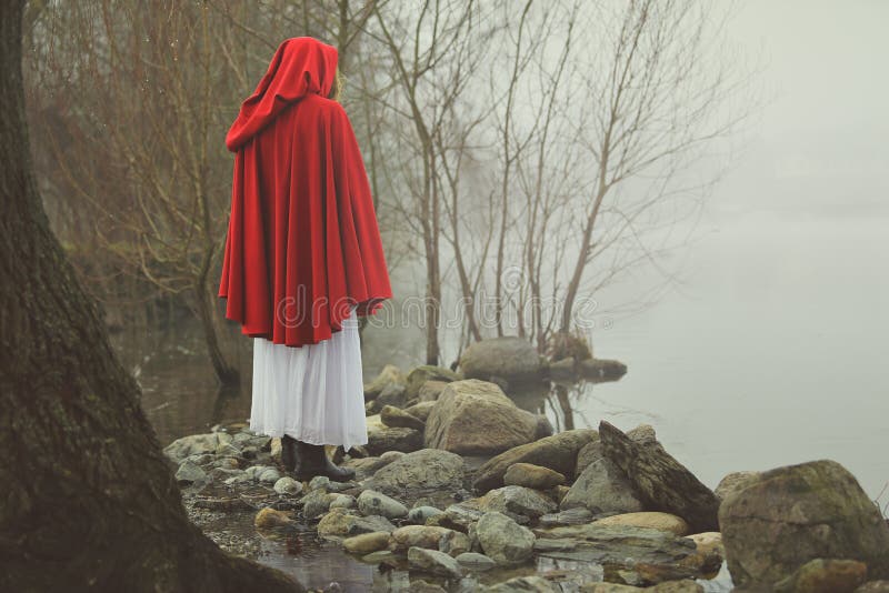 Little red riding hood on a shore of a misty lake royalty free stock photo Little red riding hood on a shore of a misty lake royalty free stock photo