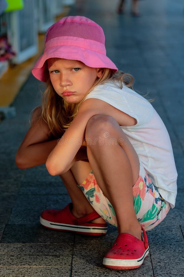Little resentful girl squatting in summer day royalty free stock images