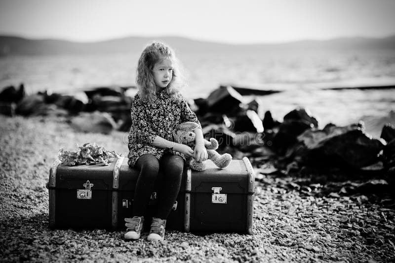 httpslittle sad girl toy sitting large suitcase near th sea looks distance image120276204