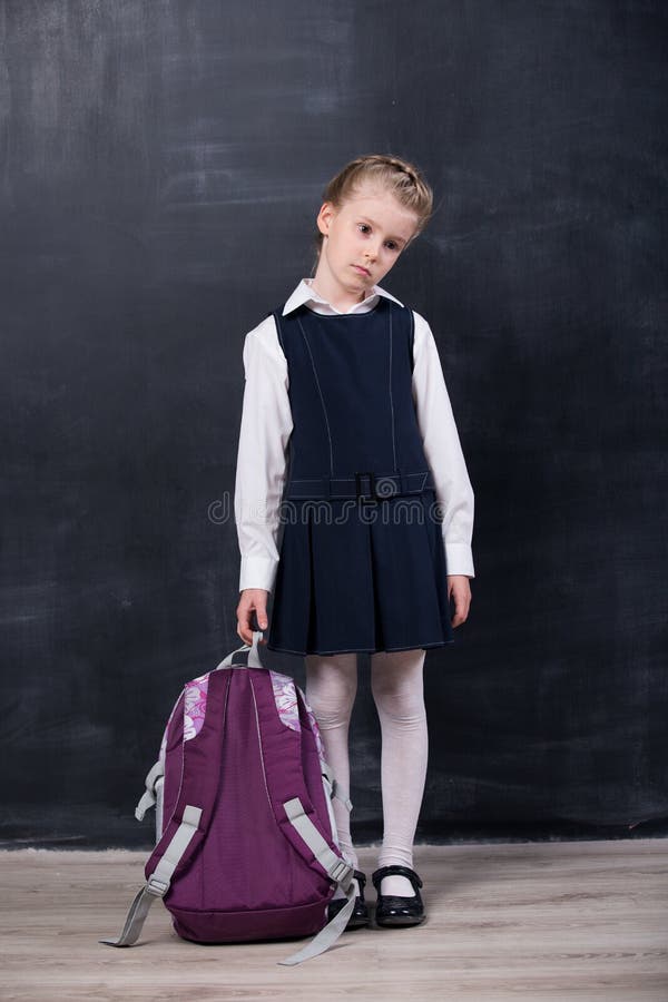 Little schoolgirl with backpack near blackboard