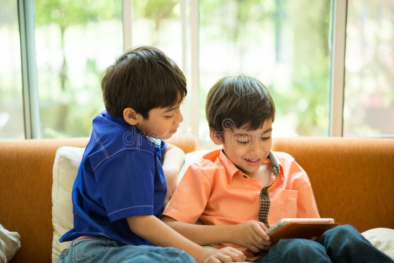 Little sibling boy playing game on mobile together house living room royalty free stock images Little sibling boy playing game on mobile together house living room royalty free stock images