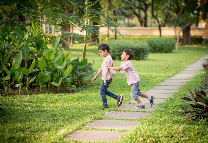 Little sibling boy playing plane paper in the park outdoor