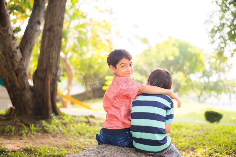 Little sibling boy sitting together in the park outdoor