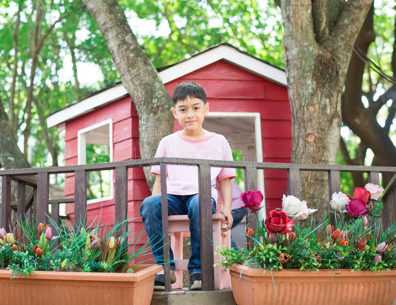 Little sibling boy sitting in the tree house eating ice cream