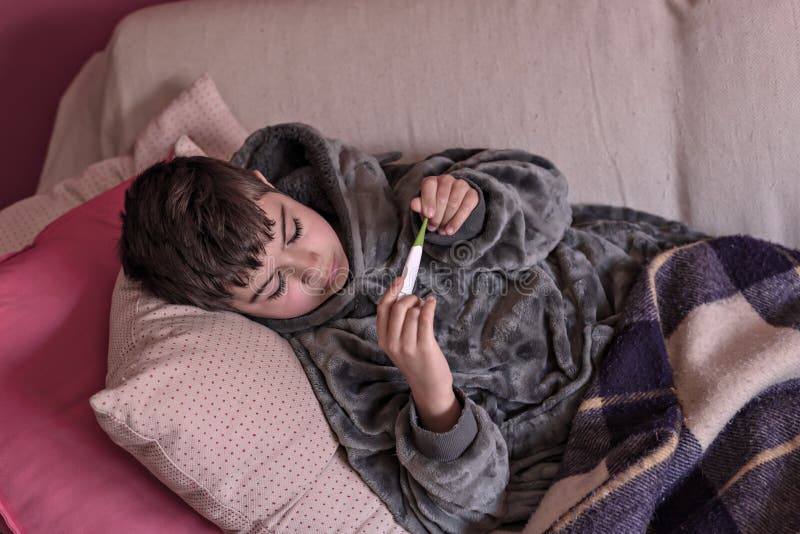 Little Sick Boy Lying on Bed with Digital Thermometer. Stock Image