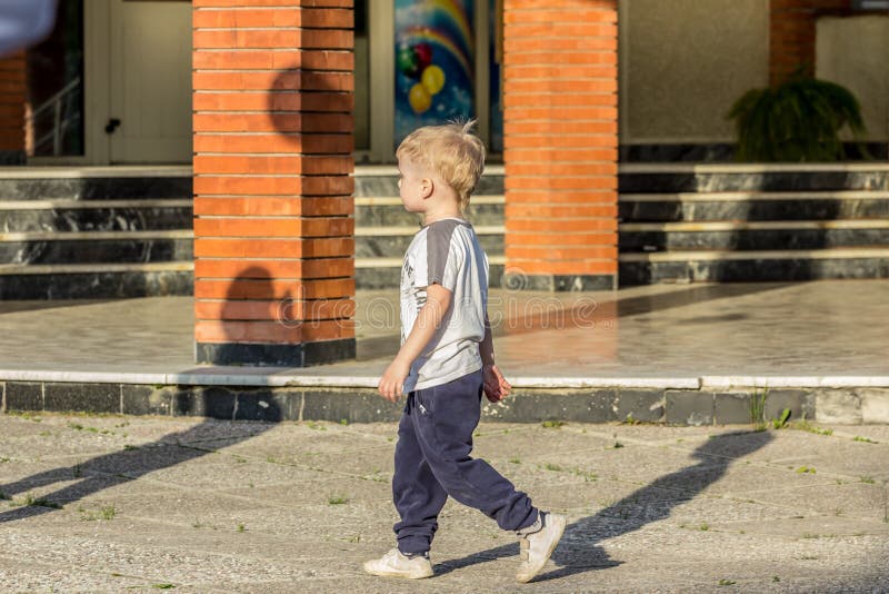 A little single boy walking in the yard, side view. Friendship of school boys.