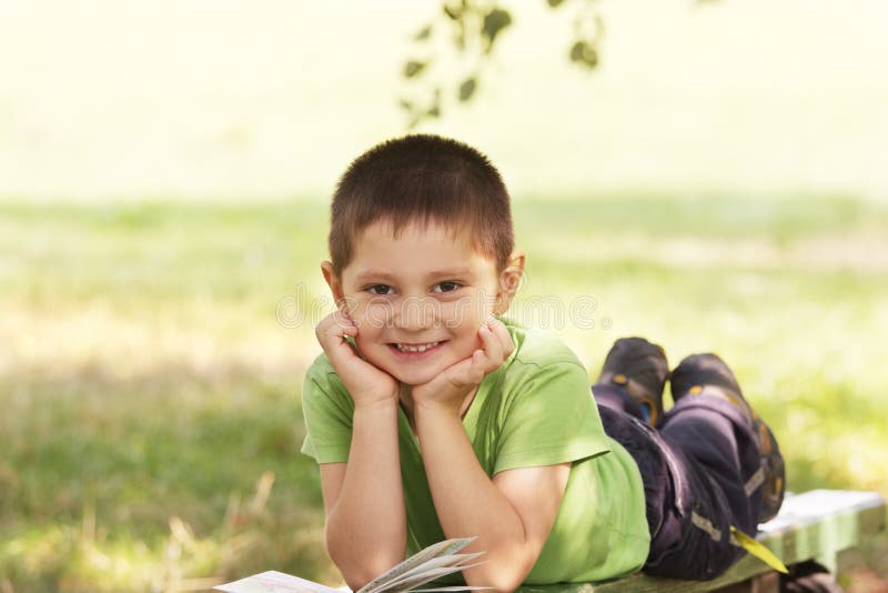 Little smiling kid with book in park