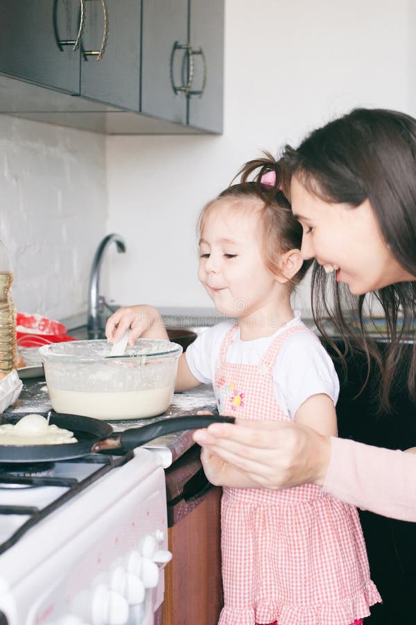 Little sweet girl and her mother fry pancakes at the traditional Russian holiday Carnival Maslenitsa Shrovetide stock images Little sweet girl and her mother fry pancakes at the traditional Russian holiday Carnival Maslenitsa Shrovetide stock images