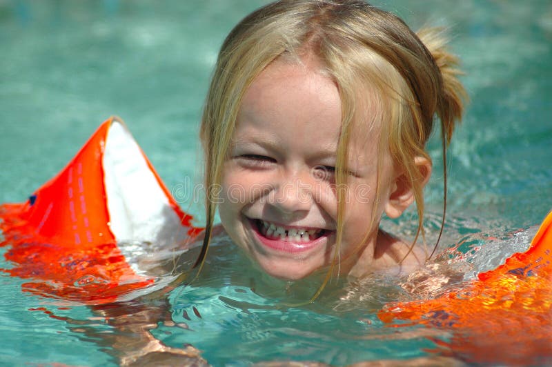 Outdoor portrait eines kleinen niedlichen kaukasische Mädchen Kind mit fröhlich lachenden Gesichtsausdruck Menge Spaß haben, während Sie im pool schwimmen.