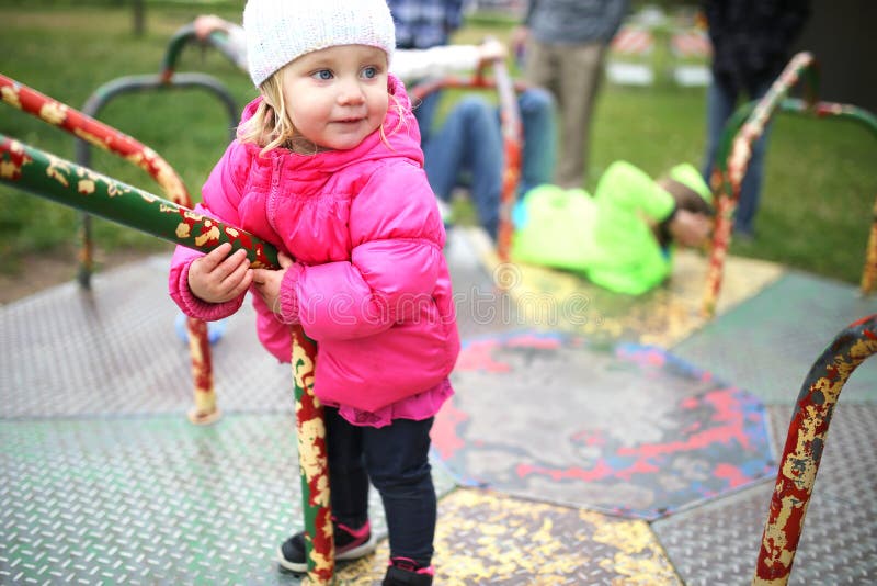 Little Toddler Girl Playing on Merry-Go-Round at Playground stock image Little Toddler Girl Playing on Merry-Go-Round at Playground stock image