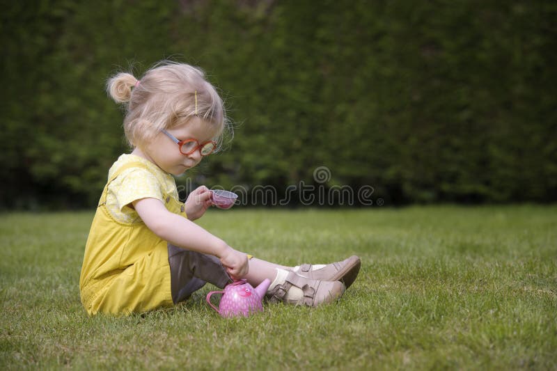 Little toddler playing tea time outdoors