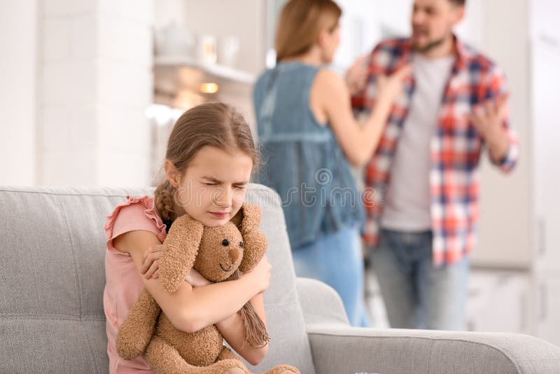 Little unhappy girl sitting on sofa while parents arguing royalty free stock image Little unhappy girl sitting on sofa while parents arguing royalty free stock image