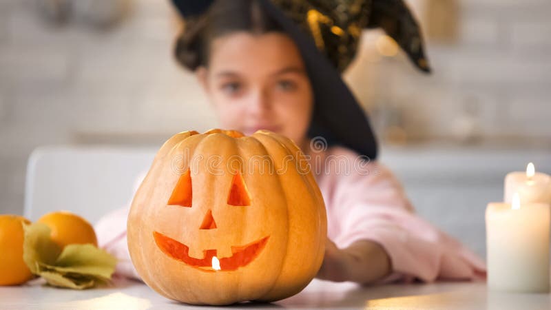 Little witch showing scary Jack-o-Lantern pumpkin, preparing for Halloween party royalty free stock photography Little witch showing scary Jack-o-Lantern pumpkin, preparing for Halloween party royalty free stock photography