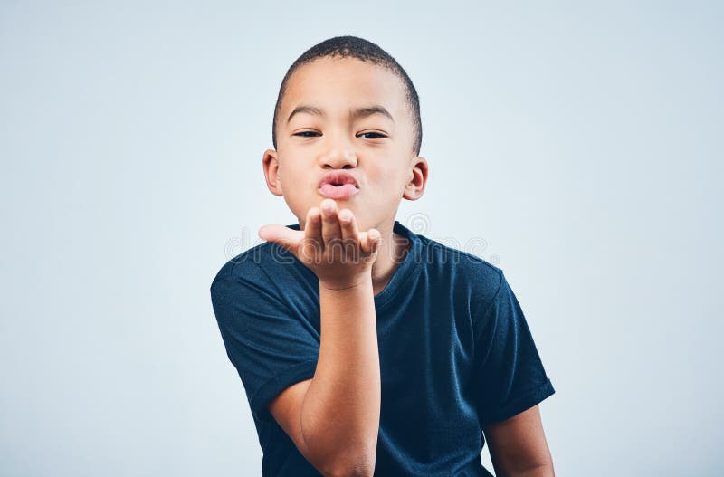 The littlest hearts are filled with lots of love. Studio shot of a cute little boy blowing kisses against a grey background