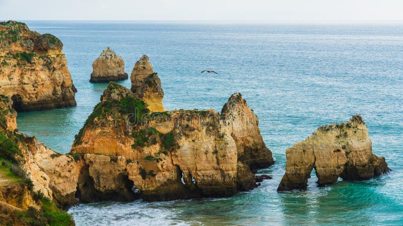 Rugged shoreline with cliffs and caves, set against the backdrop of the Atlantic Ocean's waves crashing on the rocks. Algarve, Portugal. Rugged shoreline with cliffs and caves, set against the backdrop of the Atlantic Ocean's waves crashing on the rocks. Algarve, Portugal