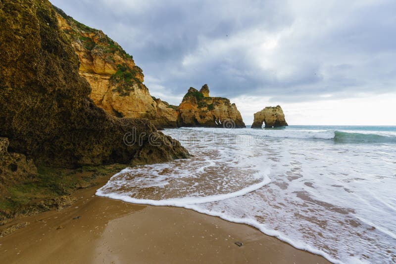 Rugged coastline adorned with natural arches and caves, where turbulent ocean waves meet the rocky shore beneath a dramatic cloudy sky, creates a captivating and atmospheric seascape. Rugged coastline adorned with natural arches and caves, where turbulent ocean waves meet the rocky shore beneath a dramatic cloudy sky, creates a captivating and atmospheric seascape