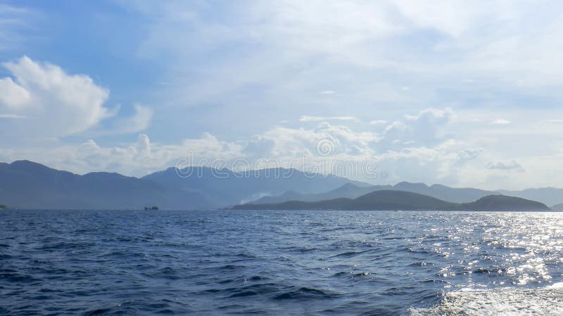 Littoral d'île de Vinperl, mer de sud de la Chine, collines, lumière du soleil, un petit bateau à l'arrière-plan, contre le ciel bleu et les nuages, le Vietnam