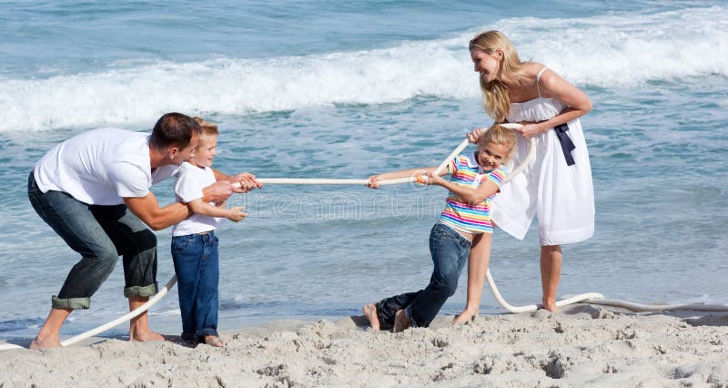 Lively family playing tug of war at the beach