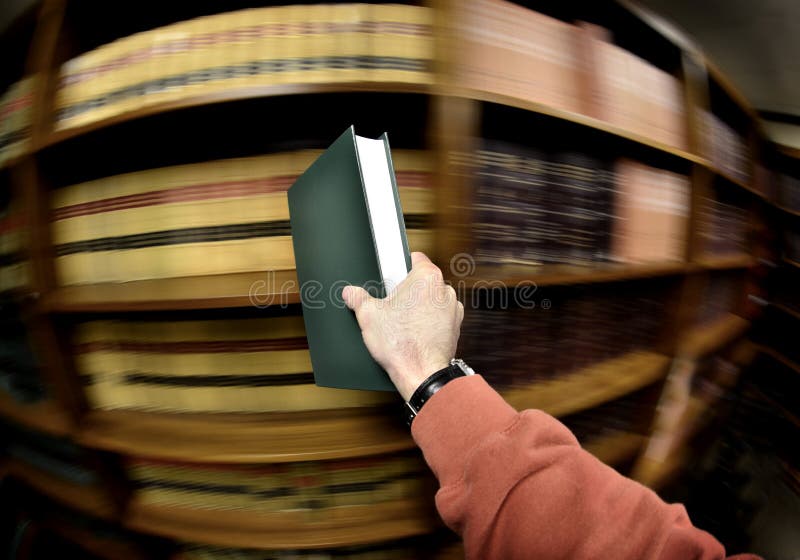 Hand holding book in an old library in background. Hand holding book in an old library in background