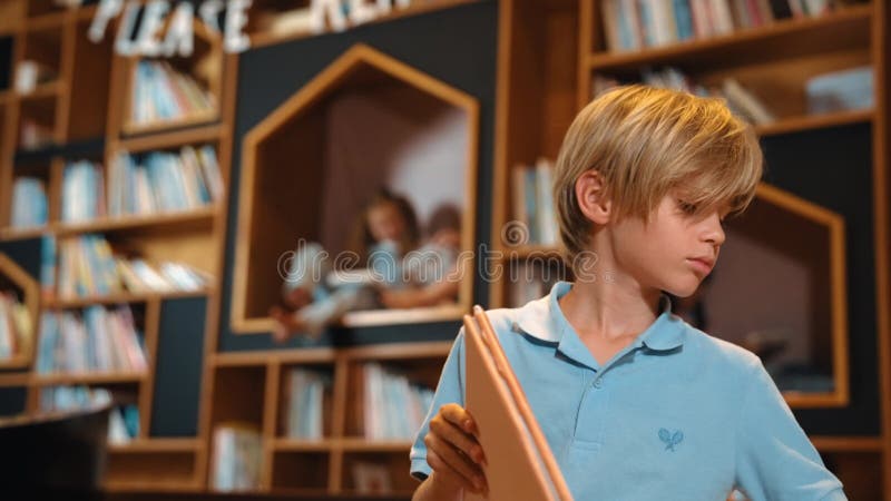 Livre de lecture de garçon attrayant tandis que groupe d'étudiants apprenant derrière. érudition. clips vidéos