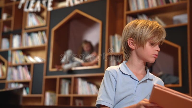 Livre de lecture de garçon attrayant tandis que groupe d'étudiants apprenant derrière. érudition. banque de vidéos