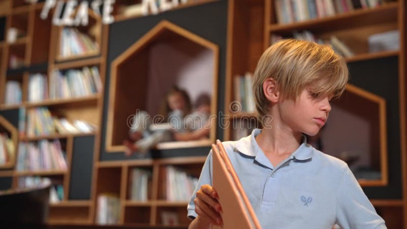 Livre de lecture de garçon attrayant tandis que groupe d'étudiants apprenant derrière. érudition. clips vidéos