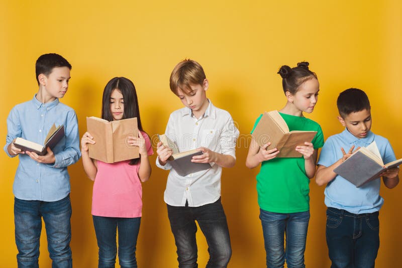 Livres de lecture futés d'enfants près de mur jaune images libres de droits Livres de lecture futés d'enfants près de mur jaune images libres de droits