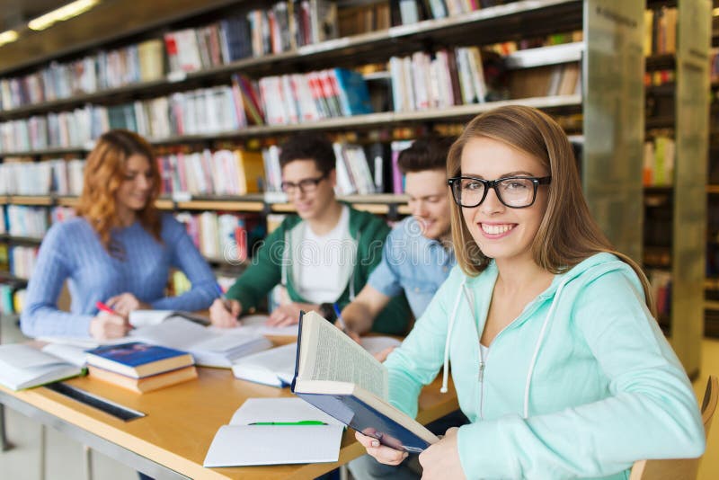Livres de lecture heureux d'étudiants dans la bibliothèque photos stock Livres de lecture heureux d'étudiants dans la bibliothèque photos stock