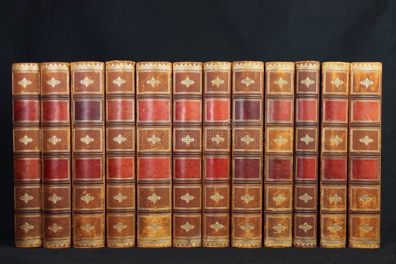 A set of twelve antique ornate brown leather books photographed over black. A set of twelve antique ornate brown leather books photographed over black
